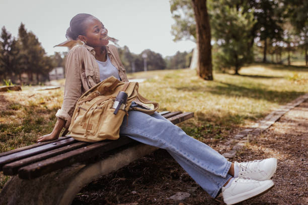 istock Person resting on bench with bottle and backpack visible. 2161767678