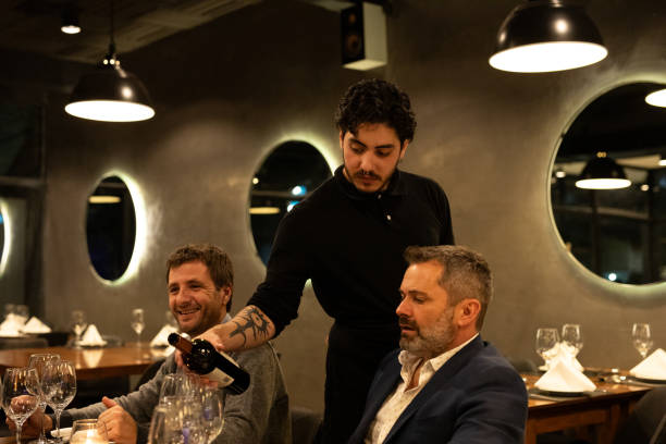istock Waiter serving wine to male friends diners 2161767900