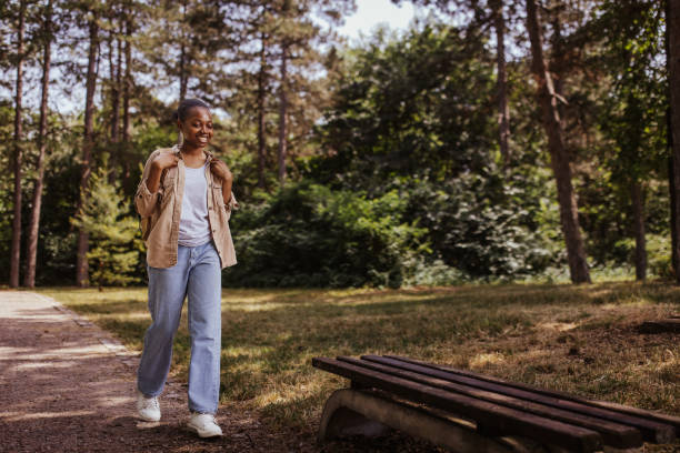 istock Person walking on park path surrounded by green trees. 2161768029