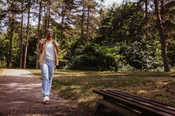 istock Person walking through park with trees and bench visible. 2161768050