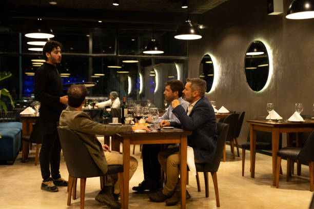 istock Waiter advising three diners about gastronomic options 2161769464