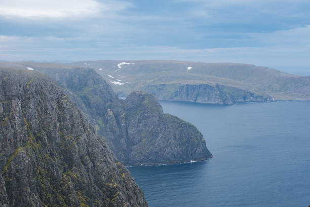 A panoramic view of the dramatic coastline of Norway, showcasing towering cliffs, rugged terrain, and a vast expanse of blue ocean. Nordkapp, North Cape