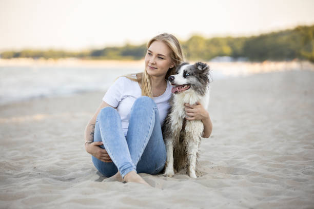 istock Young woman resting on sandy beach with her dog during summer day 2161775802