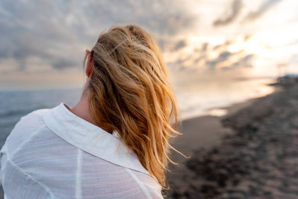 Rear view of a blonde woman on the beach at sunset