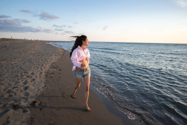 Full length of happy relaxed woman enjoying sunset on the beach