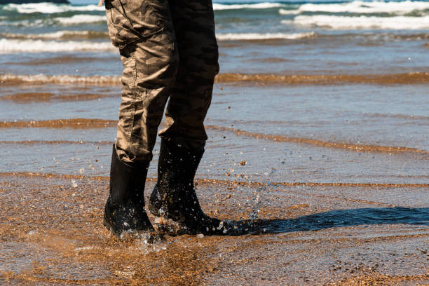 A person who wants to enjoy the cold water of the sea, solves the problem by putting on a pair of waders to be able to jump over it and splash around as if it were a puddle. Copy Space.Lastres-Colunga(Asturias -Spain)