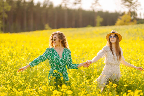 Attractive two woman in the blooming field. Nature, vacation, relax and lifestyle. Summer landscape.