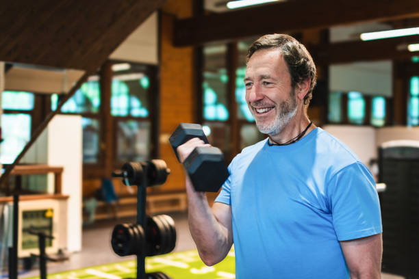 istock A man is smiling while lifting a pair of dumbbells. He is in a gym 2161796239