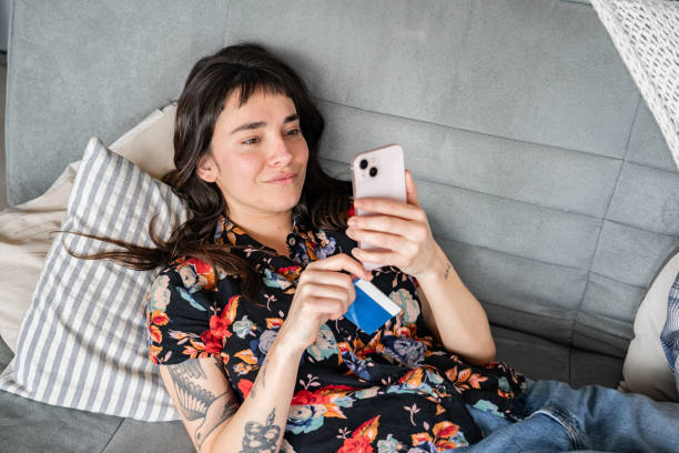 istock Young woman using mobile phone on sofa at home 2161797178