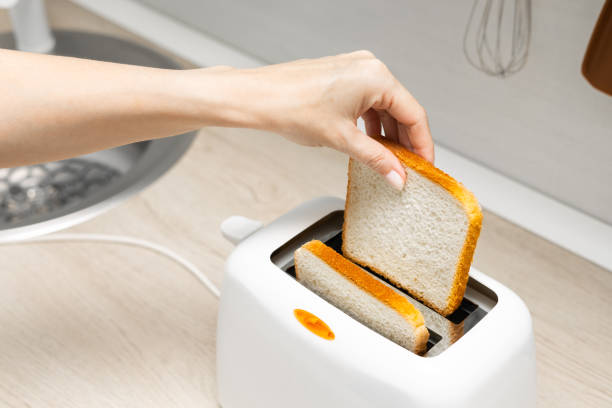 istock woman's hand putting bread into the toaster. 2161797891