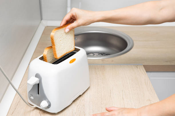 istock woman's hand putting bread into the toaster. 2161797905
