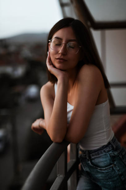 Female Closing Eyes While Relaxing On Balcony During Sunset