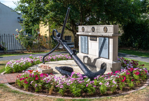 Large Nautical Anchor Sculpture Resting in Public Park With Trees and Fence