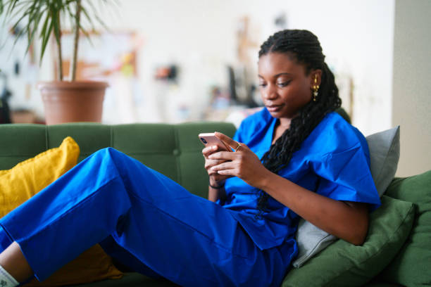 istock Woman in scrubs using mobile phone at home. 2161806929