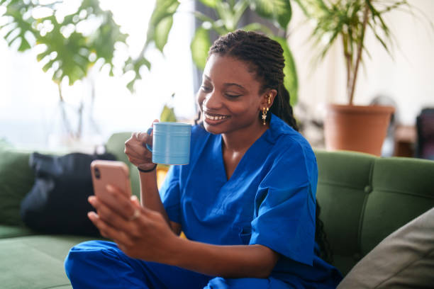 istock Woman in scrubs using mobile phone at home. 2161808279