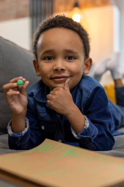 Happy boy sketching with colorful pens creates beautiful artwork enjoying the leisure activity on couch