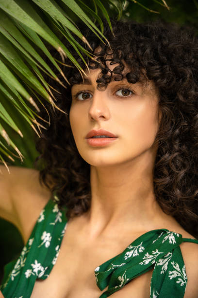 istock Curly haired woman among tropical greenery 2161809634