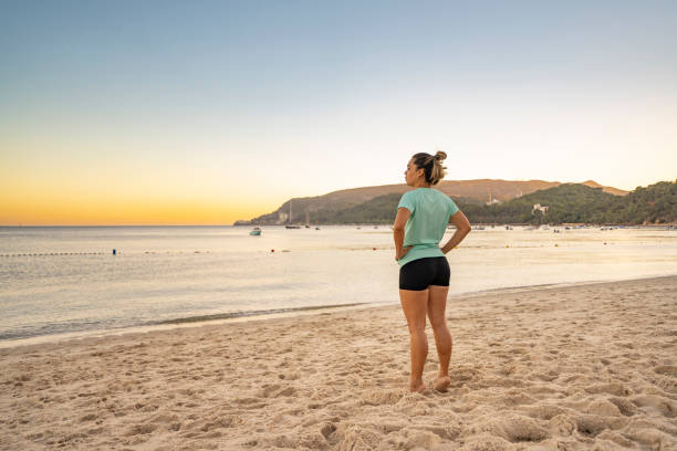 istock Woman watching the sunrise on the beach 2161814162