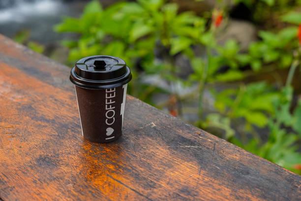 Paper cup of coffee on wooden table background