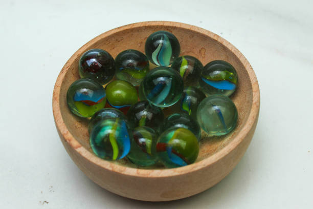 A close up photograph of a  collection of old, worn, chipped, colorful glass marbles at a flea market.