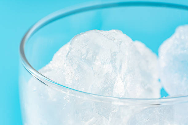 Glass with ice on light blue background