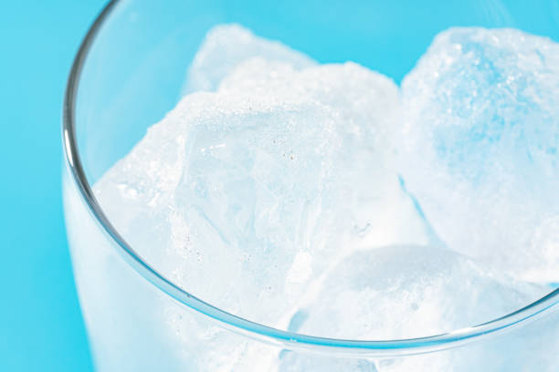 Glass with ice on light blue background