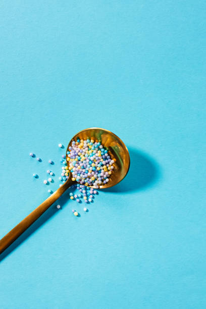istock Golden spoon with colorful sprinkles on blue background 2161829262