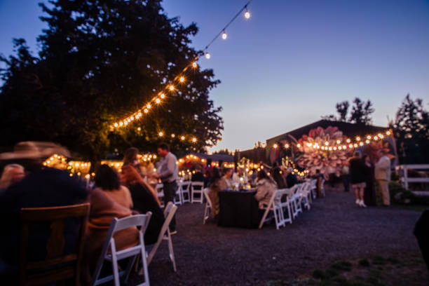 Outdoor Wedding Reception at Night Outdoor Wedding Reception at Night. Long exposure of an outdoor wedding ceremony at twilight and guests having a fun celebrating. Motion blur makes any people unrecognizable. Barn and string lights set the scene for the style. garden lights candle stock pictures, royalty-free photos & images
