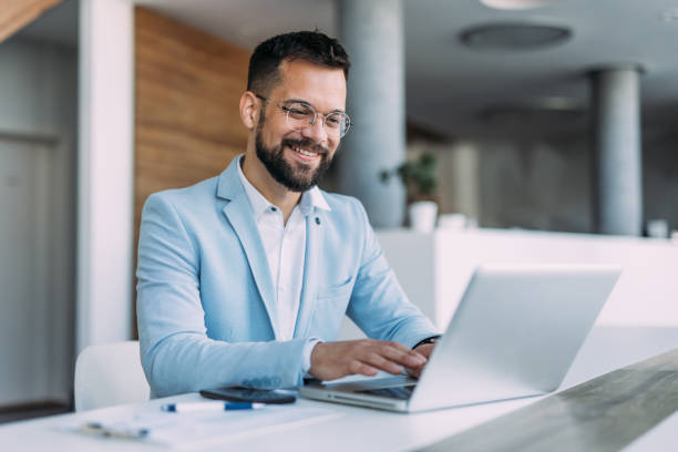 Successful businessman in modern office working on laptop.