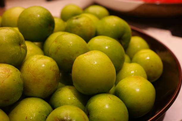 Green plums in a bowl on a table