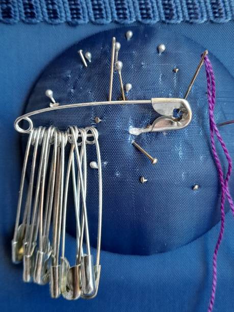 istock Safety pins and needles on blue fabric 2161847369