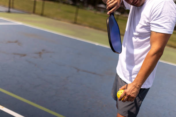 istock Man uses his wristband to wipe sweat while playing pickleball 2161851848