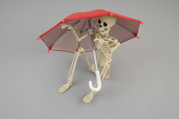 istock Human skeleton sitting under red umbrella 2161855555