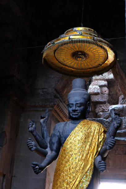 A devotional and serene moment as two visitors honor a decorative shrine within Angkor Wat Temple in Cambodia.