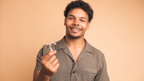 istock Happy young man showing invisible braces in beige studio 2161861057