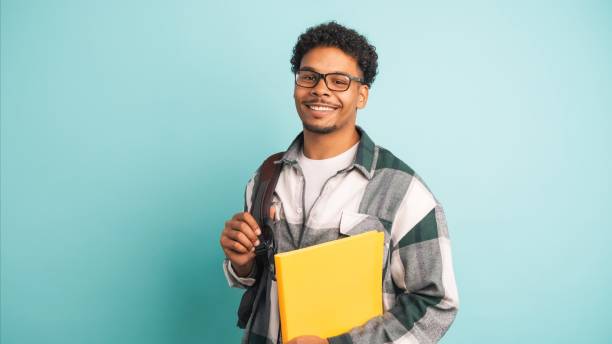 istock Happy male university student with backpack and books in blue studio 2161861099