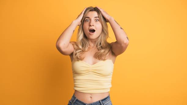 istock Smiling young woman standing with widened eyes on yellow background 2161864543