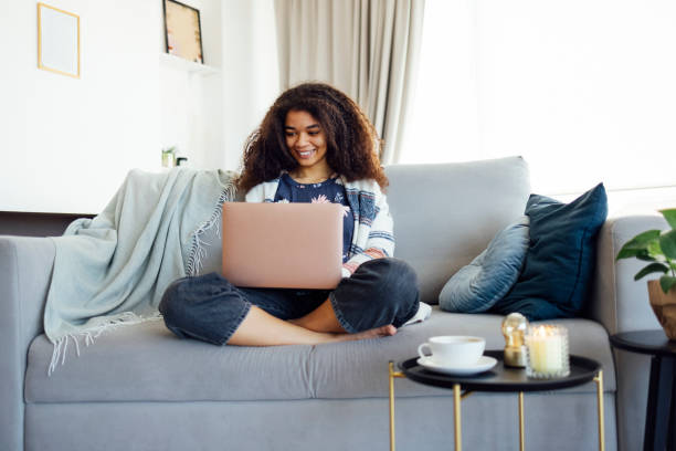 istock Excited cheerful young black woman using laptop computer on sofa at home 2161866917