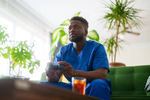 istock Man in scrubs playing video game at home. 2161868113