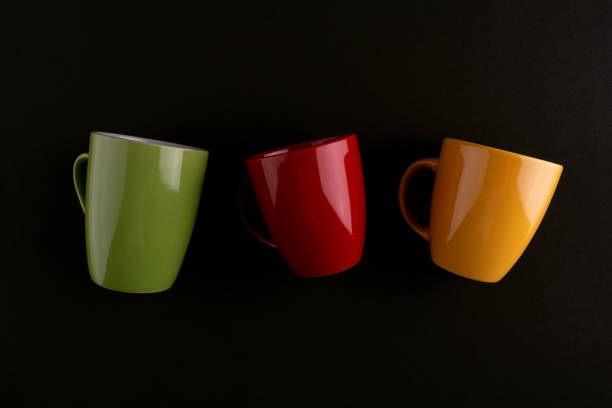 Coffee cups on black background. Green cup. Yellow mug. red cup