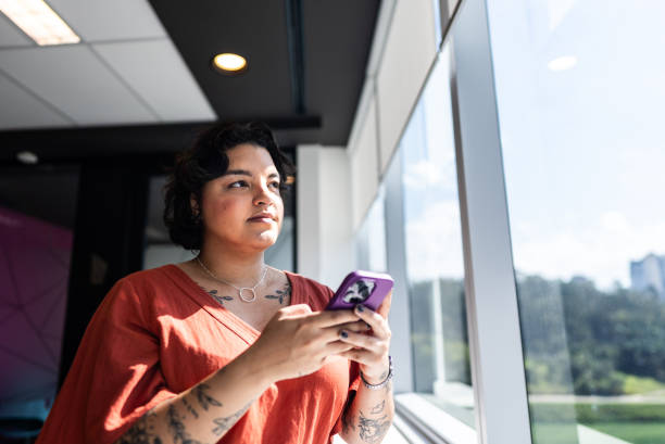 istock Businesswoman using mobile phone and looking through window on the office 2161871146