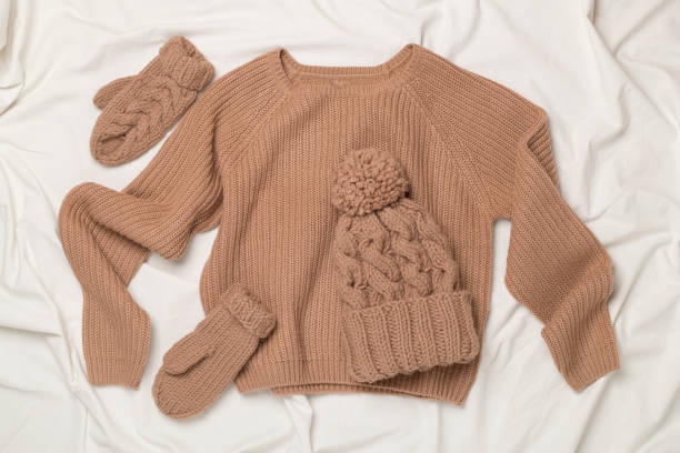 istock Sweater and winter hat with mittens on white bed sheet, top view. 2161884048