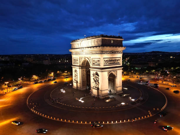 Paris Arc de Triomphe Triumphal Arch at Chaps Elysees at night, Paris, France. Drone view, Eiffel Tower in the background.  Architecture and landmarks of Paris. Postcard of Paris