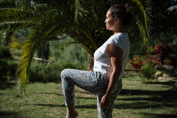 istock Woman practicing yoga outdoors in nature under a palm tree 2161888301