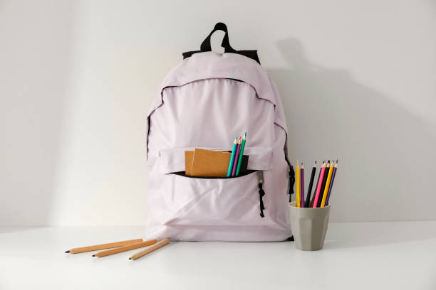 istock Backpack with school supplies and stationery on white table. Back to school concept. 2161890723