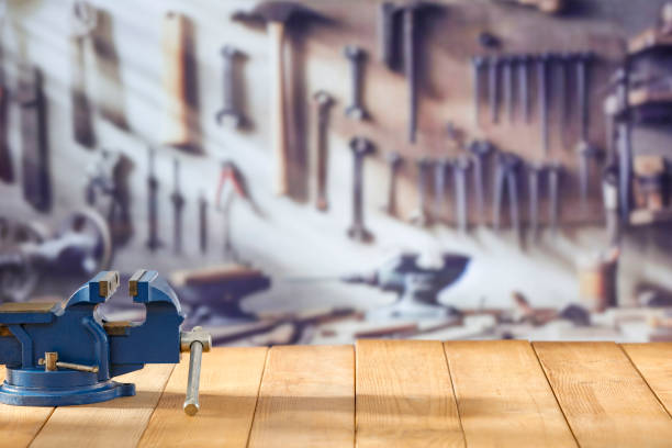 Mechanic bench vice on a wooden workbench in a craftsman's workshop.