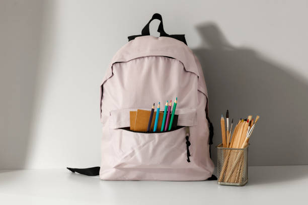 istock Backpack with school supplies and stationery on white table. Back to school concept. 2161890799