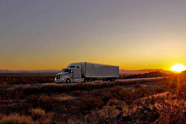 white truck trailer on highway at sunset and mountains in the background