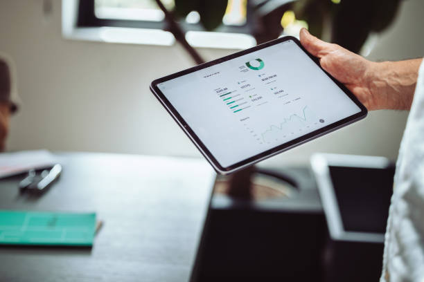 istock Person Holding Tablet Displaying Business Data in Office 2161896254