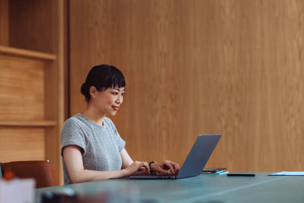 istock Focused Asian Woman Working on Laptop in Modern Office 2161896264